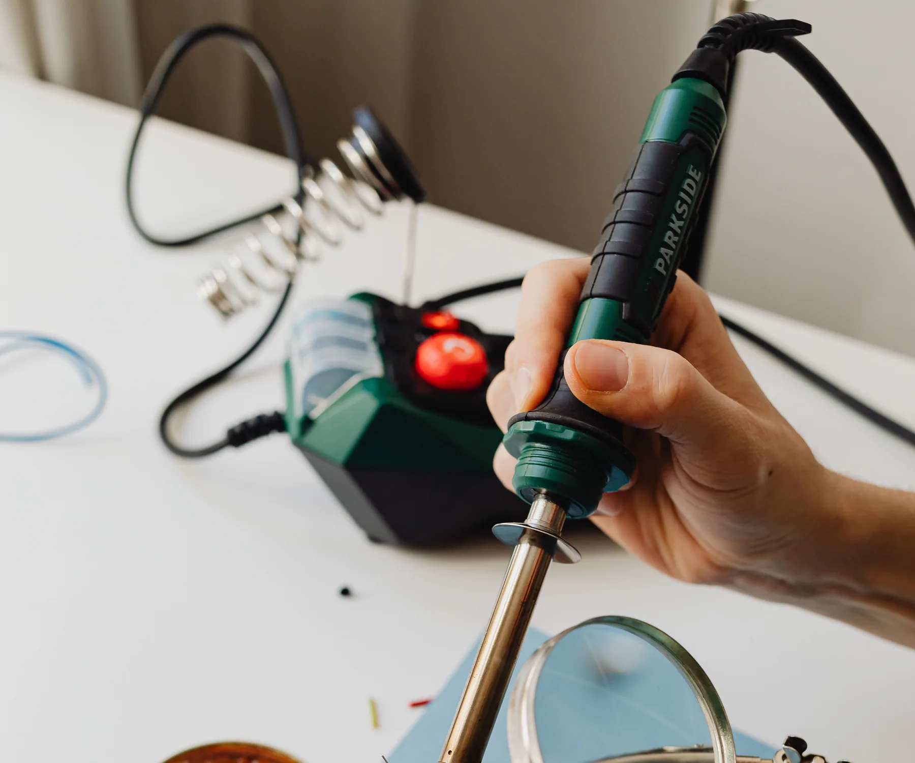 Hands performing controlled soldering work on an electronic board