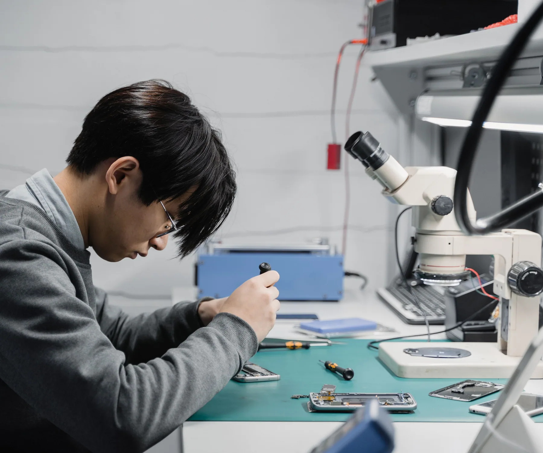 Technician using magnification while repairing mobile devices on a workbench